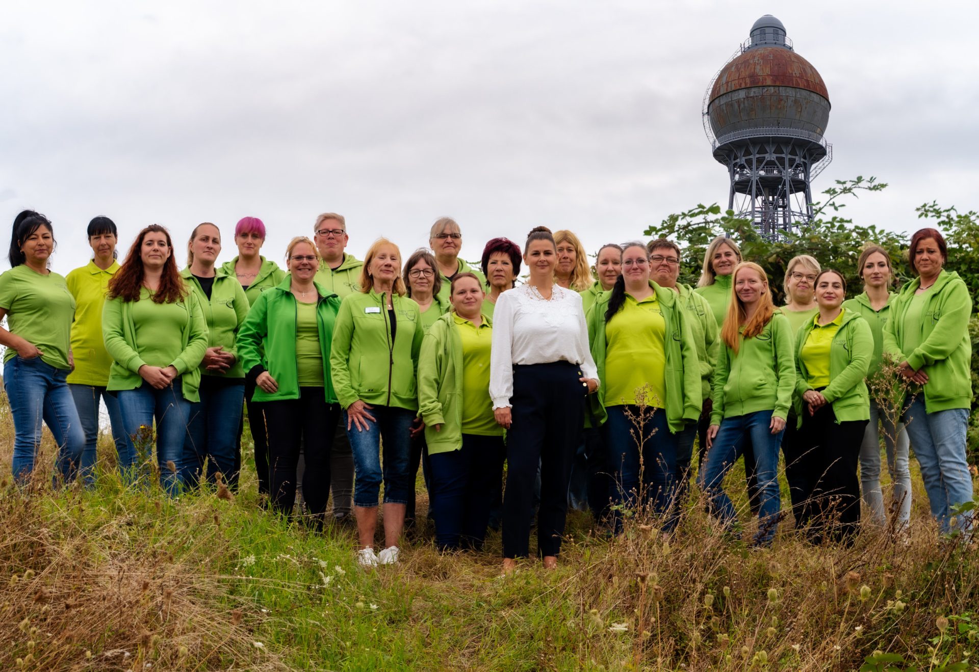 Das Team der Gloger Hausdienste auf einer Wiese vor dem Ilseder Wasserturm